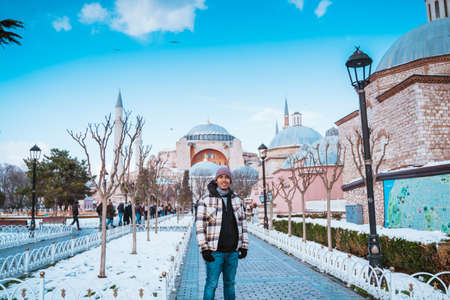male tourist visiting hagia sophia. man smiling in front of turkey most popular mosque attractionの写真素材