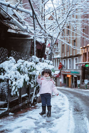 cute little girl in the city cover with snow during winterの写真素材