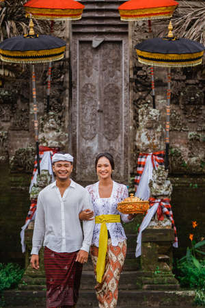 couple with balinese traditional clothing walking in front of pura gateの写真素材