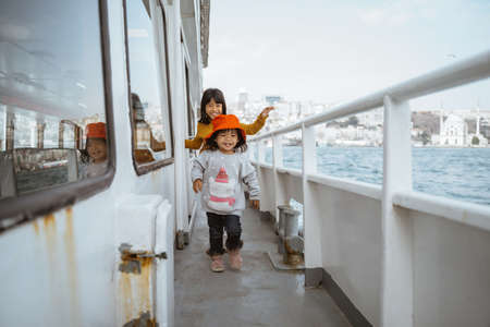 happy two little girl running around the ferryboatの写真素材