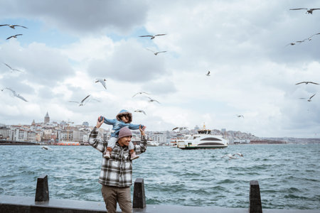 father carrying daughter on his shoulder enjoying the view of bosphorus straits with so many...