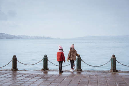 two friend kid looking at the sea standing on a side dock taken from behindの写真素材