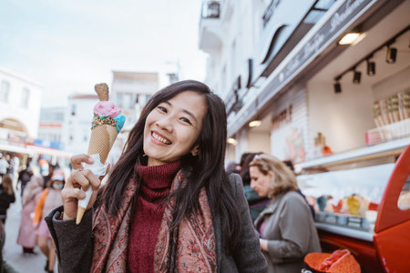 beautiful young asian woman holding ice cream smiling to camera