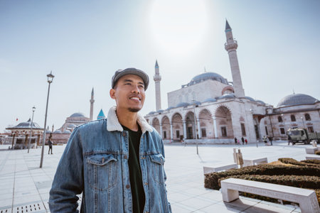 muslim young man standing in front of the mosque and mevlana museum in konya turkeyの写真素材