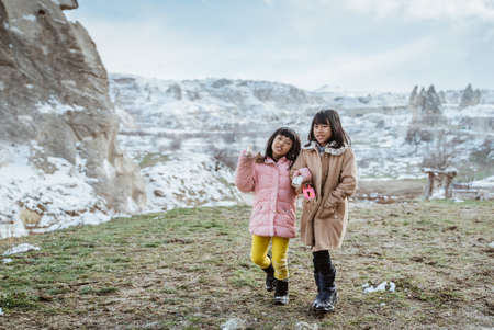 two little girl walking together and hold hand outdoor in the snowの写真素材