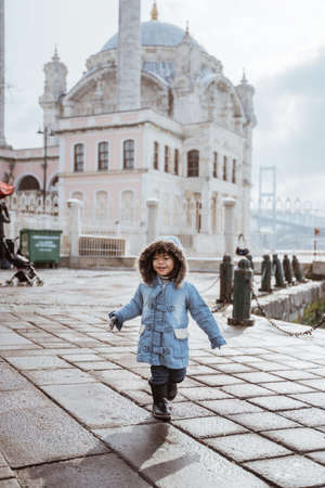 happy kid running around the square in turkey with ortakoy mosque in the backgroundの写真素材
