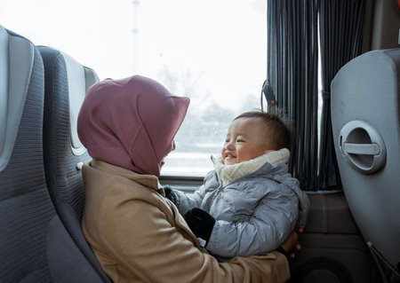 smiling muslim mother and toddler sitting inside the bus playing together