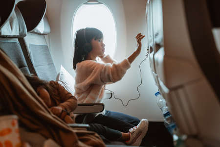 portrait of kid sitting on an airplane and watching movie from the screen at the front seatの写真素材