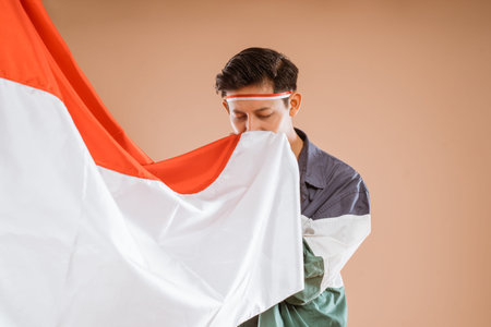 portrait of male athelete kissing indonesian flagの写真素材