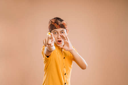 gesture of young balinese male making announcement over isolated backgroundの写真素材