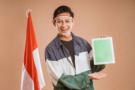 excited male athelete from indonesia using tablet pc over isolated backgroundの写真素材