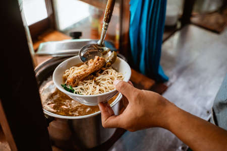 close up of sellers hand put chicken on noodles in a bowl for topping when preparing dishesの素材 [FY310190689395]