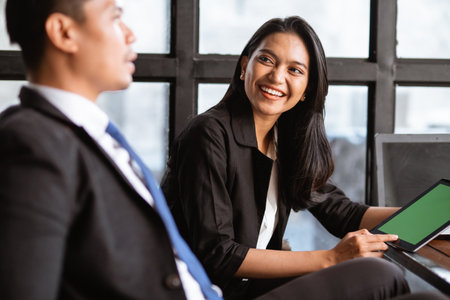 happy asian businessman and woman having a relaxed meeting using tablet in cafeの写真素材