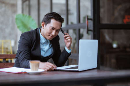 asian businessman thinking about business strategy while relaxing in coffee shopの写真素材