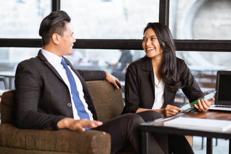 happy asian businessman and woman having a relaxed meeting using tablet in cafeの写真素材