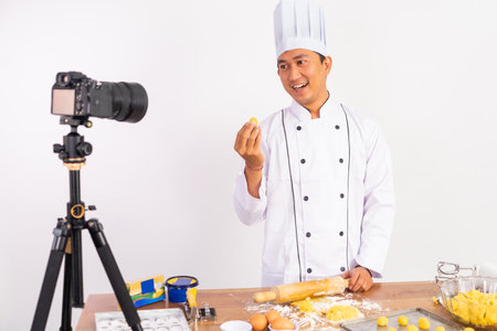 male chef food vlogger presenting cake to camera while baking cake with isolated backgroundの写真素材