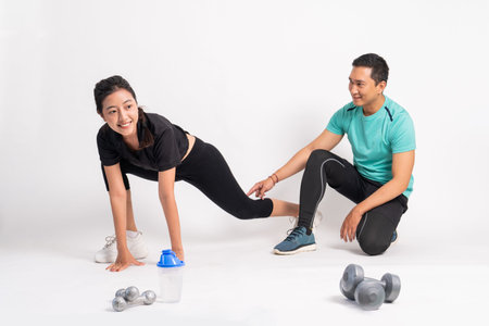 woman doing basic squat with trainer holding back knees on white background