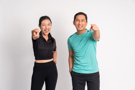 asian woman and man laughing with fingers pointing forward on isolated backgroundの写真素材