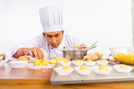 male chef looks and carefully examines cake on tray on isolated backgroundの写真素材