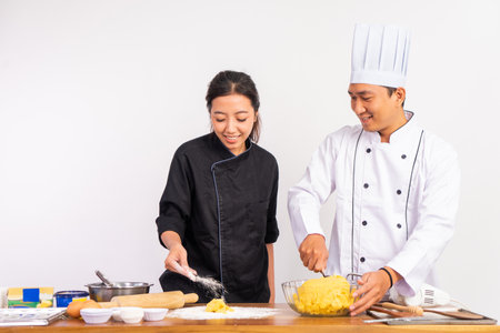 male and female chefs making cookie dough together on table on isolated backgroundの写真素材