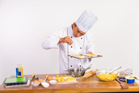 male chef sprinkles grated cheese over cake on tray on isolated backgroundの写真素材