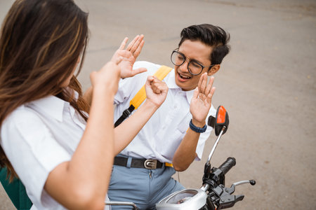 girl student wearing a high school uniform punched a boy student on a motorbikeの写真素材
