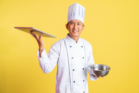 handsome male chef holding bread tray with mixing bowl on isolated backgroundの写真素材
