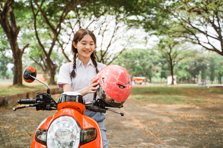 Student girl taking off helmet on motorbike with outdoor backgroundの写真素材