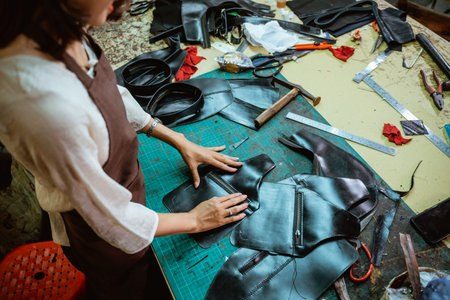 Asian craftswoman tidying tanned leather sewing in a craft workshop