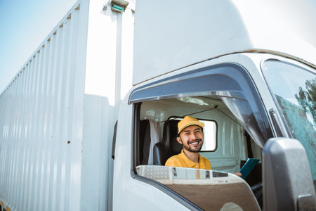 bearded male delivery man in uniform sitting smiling before leaving driving goods truck