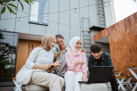 asian college students using a laptop while together hanging out in a cafe