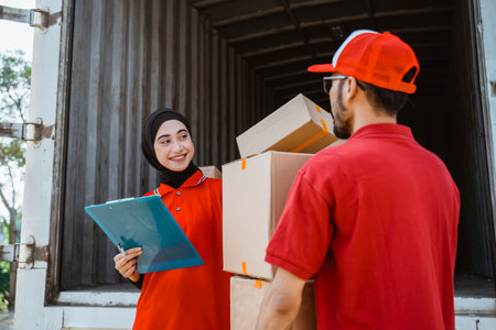Two freight forwarding service employees inspect box packages before they are shipped on a container truckの写真素材