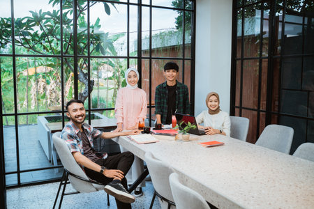 Smart Asian young people smiling at camera sitting in indoor cafeの写真素材