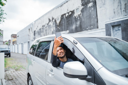 male driver searches for cell phone signal while driving a carの写真素材