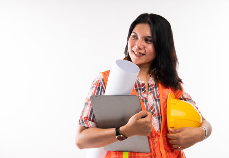 close up of the beautiful architect standing holding the digital tablet and safety equipment on isolated backgroundの写真素材