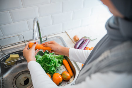 close up of moms hand washing vegetables in the sink in the kitchenの写真素材