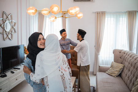muslim friends embracing during visiting family eid celebration at homeの写真素材