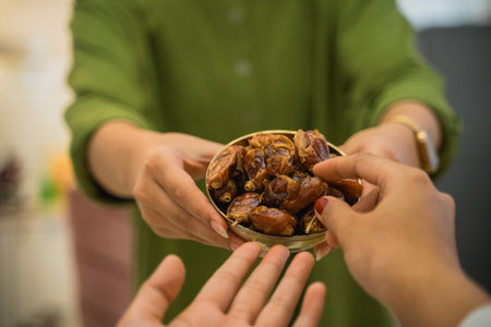 Womans hand serves a bowl of dates for iftar at homeの写真素材