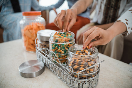 peoples hands take snacks from glass tube jars full of snacks on the table in the living roomの写真素材