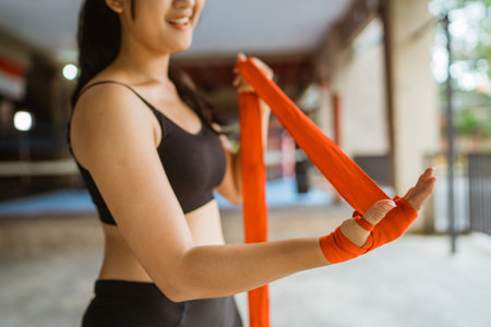 a beautiful boxer wearing the boxing gloves at her left hand while standing at the boxing studio