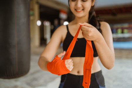 a beautiful boxer wearing the boxing gloves at her left hand while standing at the boxing studioの写真素材