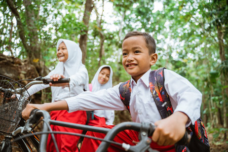 an elementary school boy riding his bike with his friends through the country roadの写真素材