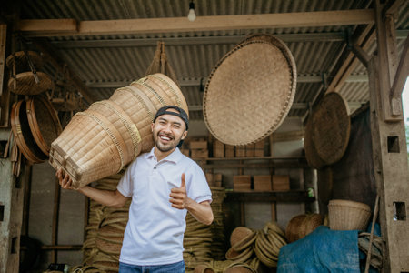 asian male seller carrying bamboo basket product in front of his shopの写真素材
