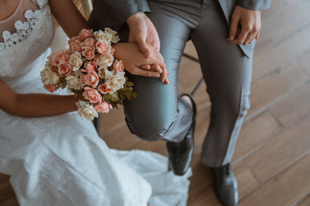 asian brides holding hands while sitting on the chair and holding the flowers bouquetの写真素材