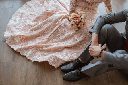 asian bride in orange gown holding the flowers bouquet while sitting together with the groom on the floorの写真素材