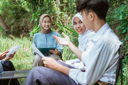 the teacher watches as one of the students is presenting during an outdoor classの写真素材