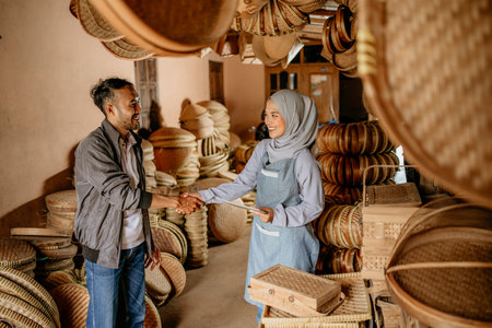 beautiful young muslim woman shake hand with customer in her woven bamboo product workshopの写真素材