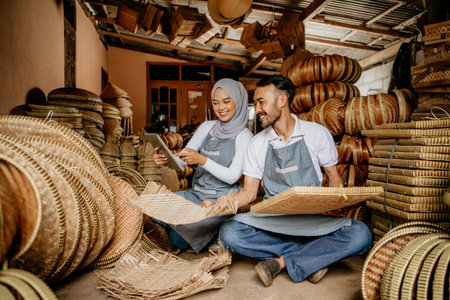 man and woman using tablet pc while working in their traditional product shopの写真素材