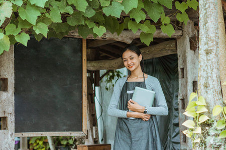 female barista in apron holding the digital tablet while standing outside the coffee shopの写真素材