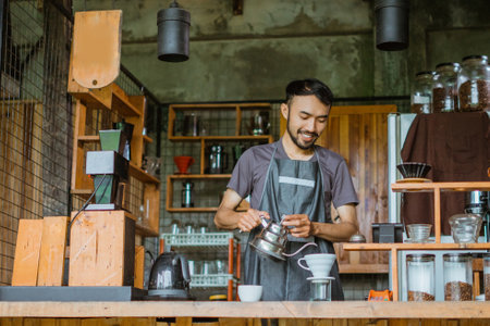 male barista in apron seriousely brewing the coffee using the v60 inside the bar deskの写真素材